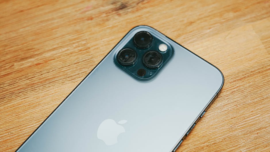 Close-up image of a sleek smartphone with triple camera on a wooden surface.