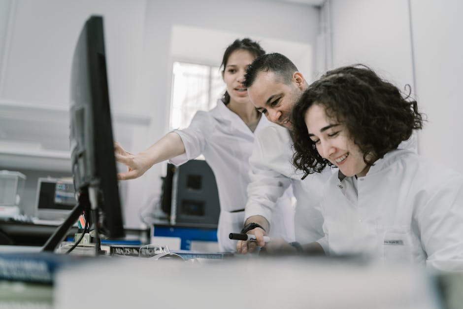 Group of diverse scientists working together on a computer in a bright, modern laboratory.